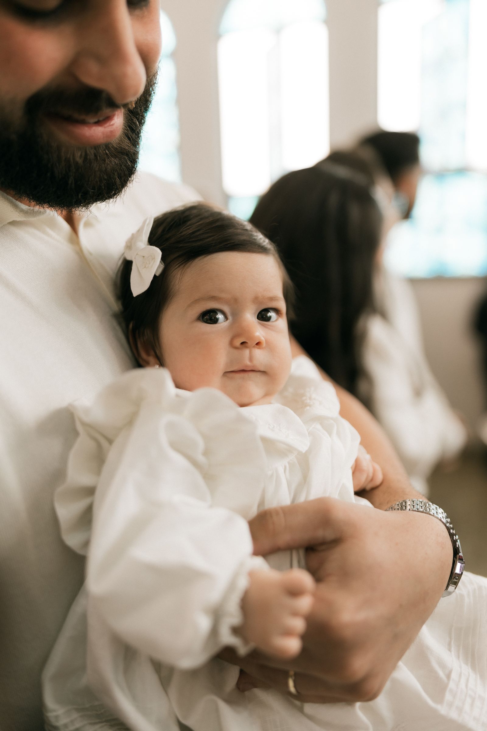 Bébé en robe de baptême blanche tenu par son père
